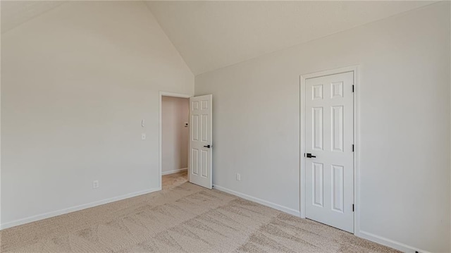 carpeted empty room featuring high vaulted ceiling and baseboards