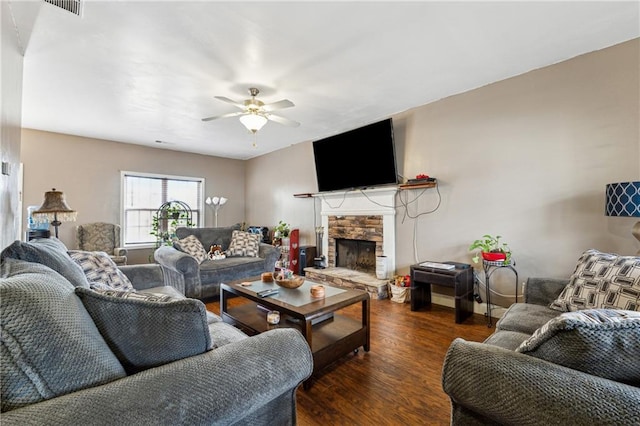 living room with a stone fireplace, dark hardwood / wood-style floors, and ceiling fan