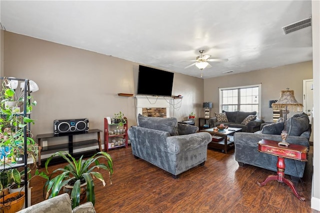 living room featuring a stone fireplace, dark hardwood / wood-style floors, and ceiling fan