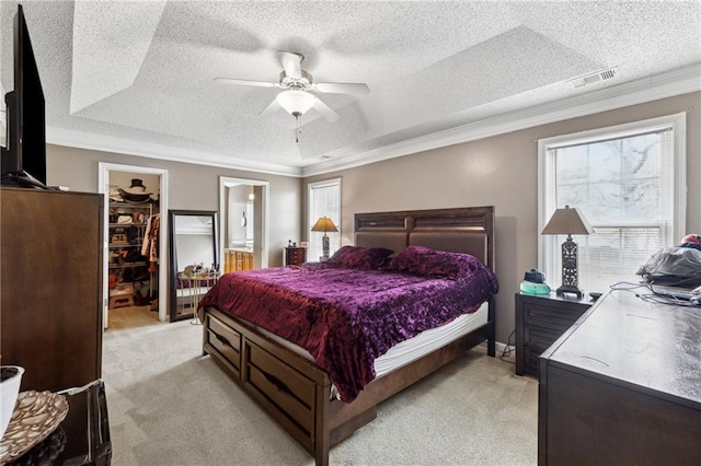 bedroom with ornamental molding, a spacious closet, light carpet, a textured ceiling, and a closet