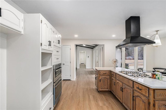 kitchen with white cabinetry, island exhaust hood, stainless steel gas stovetop, and light hardwood / wood-style flooring