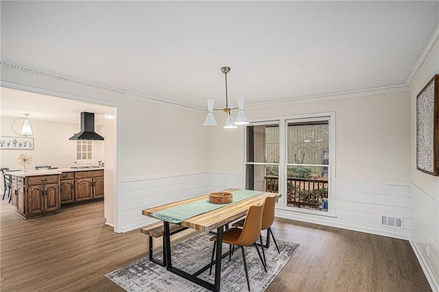 dining space featuring an inviting chandelier, ornamental molding, and wood-type flooring