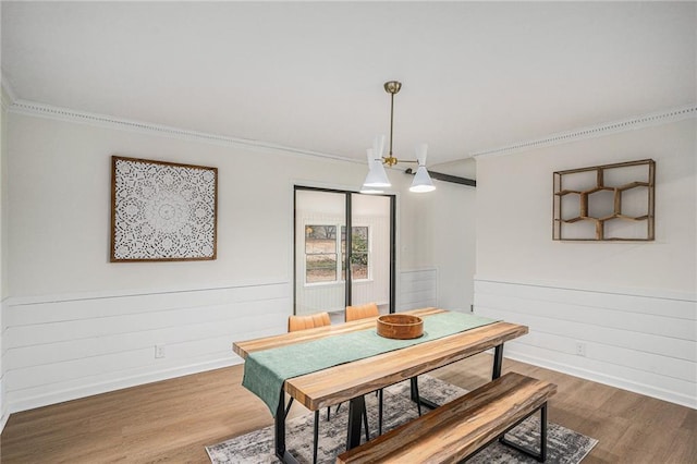 dining space with hardwood / wood-style flooring, ornamental molding, and a notable chandelier