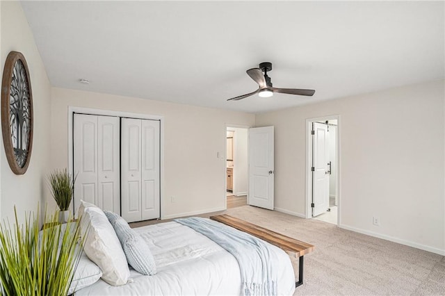 bedroom featuring connected bathroom, light colored carpet, ceiling fan, and a closet