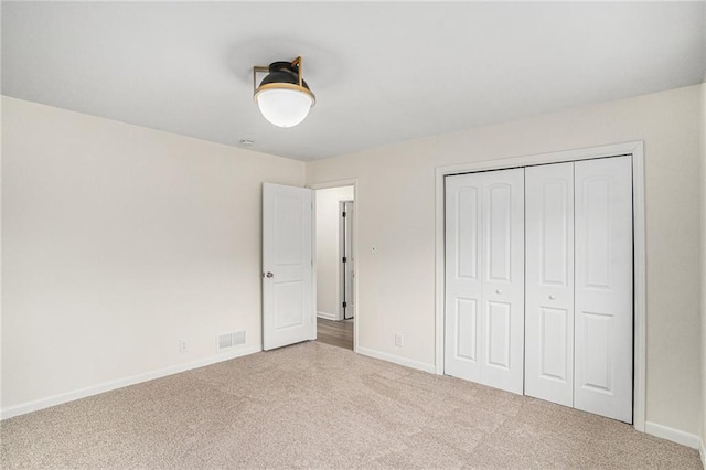 unfurnished bedroom featuring light colored carpet and a closet