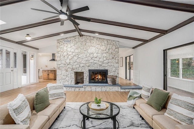 living room featuring lofted ceiling with beams, a fireplace, and light hardwood / wood-style floors