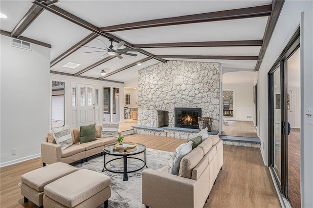 living room with lofted ceiling with beams, ceiling fan, light wood-type flooring, and a fireplace