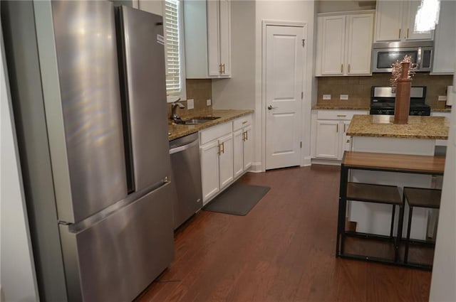 kitchen featuring white cabinetry, appliances with stainless steel finishes, dark wood-style flooring, and light stone counters