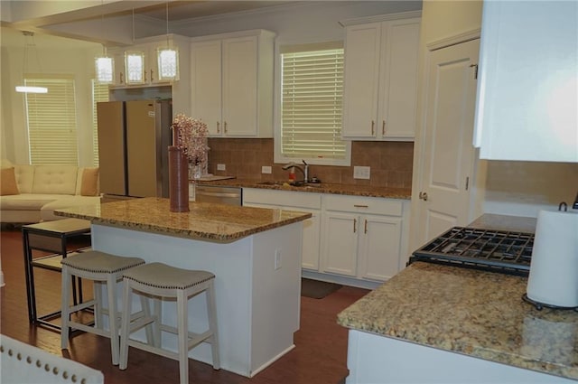 kitchen featuring stainless steel appliances, a sink, decorative light fixtures, and white cabinetry