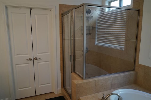 bathroom with a closet, tile patterned flooring, a shower stall, and a washtub