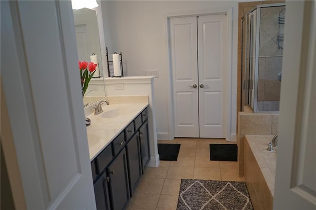 bathroom with double vanity, a stall shower, tile patterned floors, a sink, and a closet