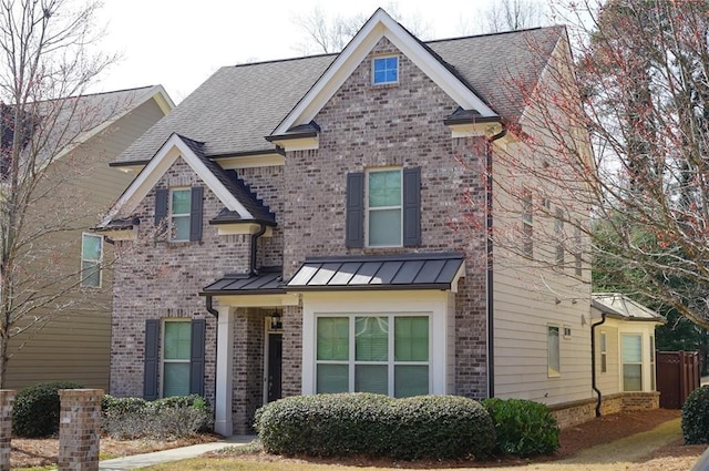 view of front of house with a standing seam roof, brick siding, metal roof, and roof with shingles