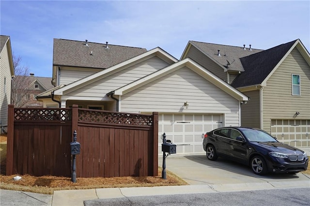 view of front of home featuring a garage, concrete driveway, roof with shingles, and fence