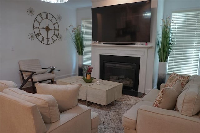 living area featuring a glass covered fireplace and baseboards