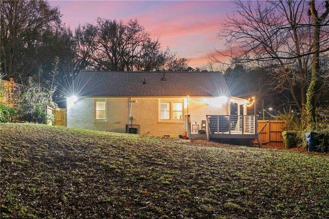 back house at dusk with a deck and central AC