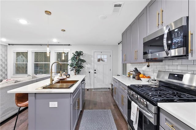 kitchen with gray cabinetry, sink, dark hardwood / wood-style floors, decorative light fixtures, and stainless steel appliances