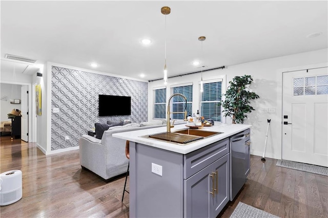 kitchen with sink, hanging light fixtures, dark hardwood / wood-style flooring, stainless steel dishwasher, and an island with sink