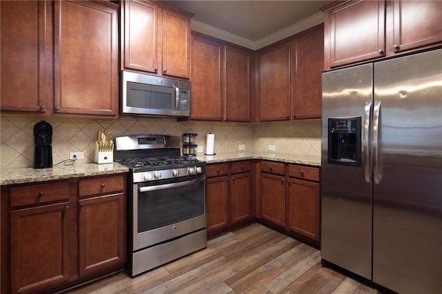 kitchen featuring tasteful backsplash, appliances with stainless steel finishes, light stone counters, ornamental molding, and light wood-style floors