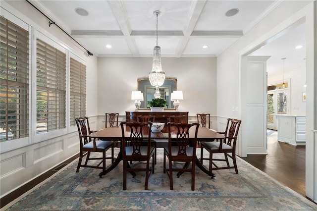 dining space featuring beamed ceiling, ornamental molding, wood finished floors, a decorative wall, and coffered ceiling