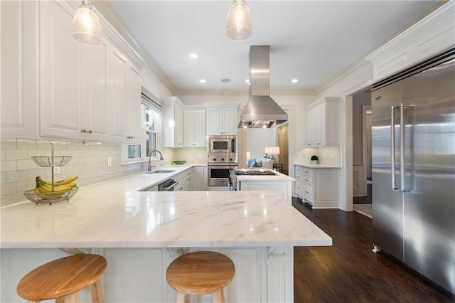 kitchen featuring built in appliances, white cabinets, island exhaust hood, and a sink