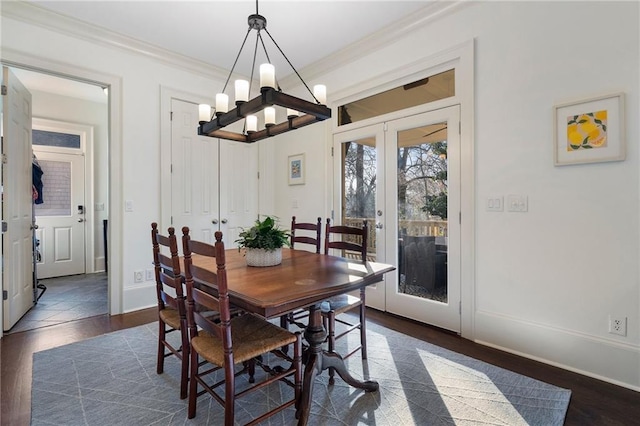 dining space featuring baseboards, dark wood finished floors, an inviting chandelier, french doors, and crown molding