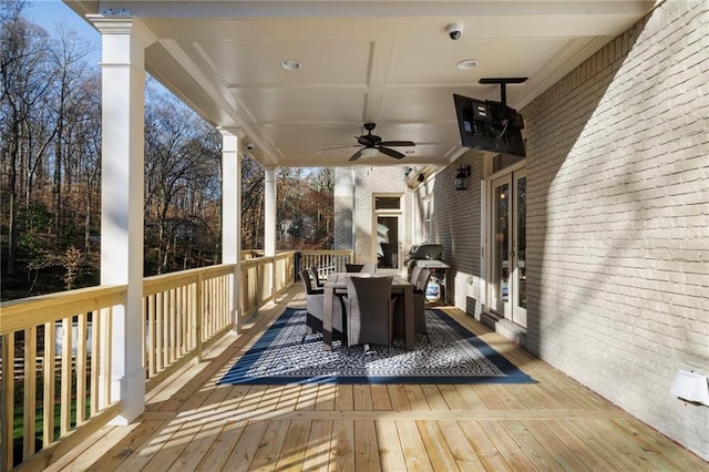 wooden deck with outdoor dining area and a ceiling fan