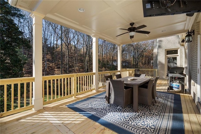 wooden deck with outdoor dining space, a ceiling fan, and grilling area