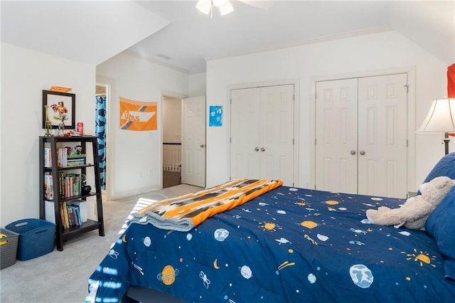 bedroom with two closets, crown molding, carpet, and a ceiling fan