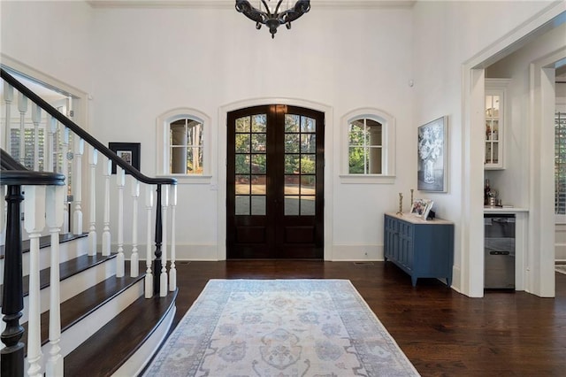 entrance foyer with dark wood finished floors, french doors, arched walkways, stairway, and baseboards