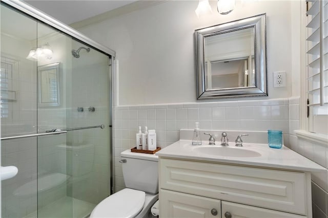 full bathroom featuring vanity, a wainscoted wall, a stall shower, tile walls, and toilet