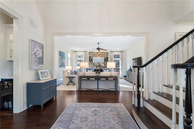 entryway with ornamental molding, a ceiling fan, wood finished floors, baseboards, and stairs