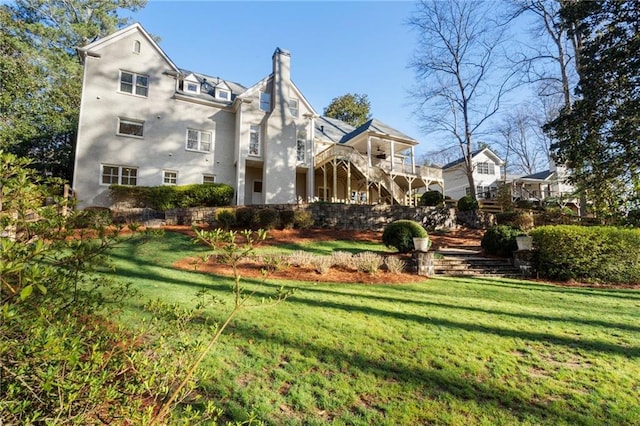 rear view of property with stairs, a yard, and a chimney