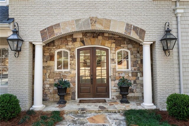 entrance to property with french doors, stone siding, and brick siding