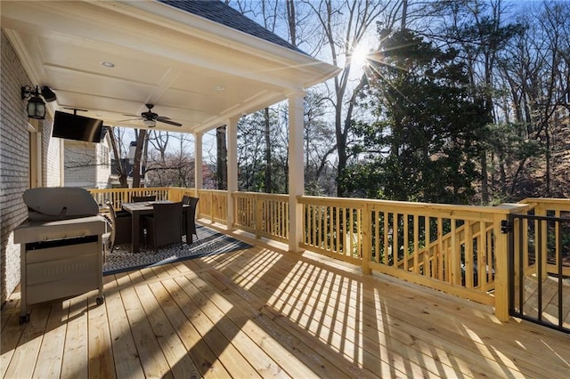 wooden deck with outdoor dining space, grilling area, and ceiling fan