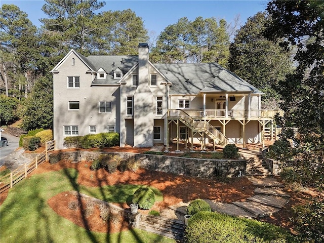 rear view of property featuring stairway, a chimney, and fence