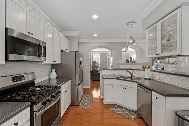 kitchen with sink, white cabinetry, hanging light fixtures, light hardwood / wood-style flooring, and appliances with stainless steel finishes