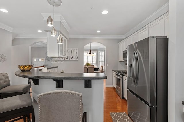 kitchen featuring white cabinetry, appliances with stainless steel finishes, a kitchen bar, and kitchen peninsula