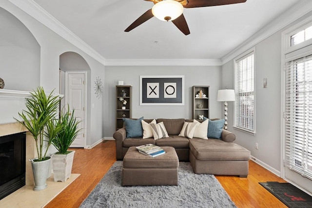 living room with ornamental molding, hardwood / wood-style floors, ceiling fan, and a high end fireplace