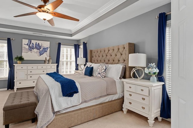 bedroom featuring crown molding, a tray ceiling, light colored carpet, and ceiling fan