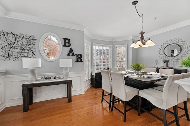 dining area with ornamental molding, light hardwood / wood-style flooring, and a notable chandelier