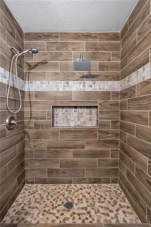 bathroom with a tile shower and a textured ceiling