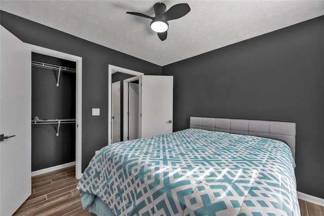 bedroom with wood tiled floor, a textured ceiling, baseboards, and a closet