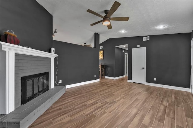 unfurnished living room featuring lofted ceiling, a brick fireplace, wood finished floors, and visible vents