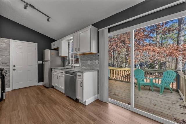 kitchen with white cabinets, appliances with stainless steel finishes, vaulted ceiling, and wood finished floors