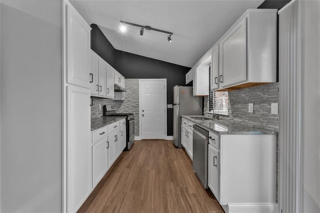 kitchen featuring stainless steel appliances, lofted ceiling, white cabinets, a sink, and wood finished floors