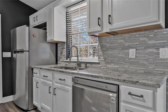 kitchen featuring light stone counters, stainless steel appliances, a sink, white cabinetry, and tasteful backsplash