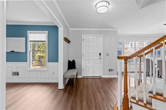 entryway with crown molding, dark wood-type flooring, and an inviting chandelier