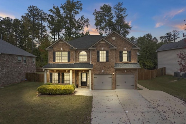 view of front of house with a yard, central AC, and a garage