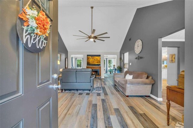 living room featuring ceiling fan, light hardwood / wood-style flooring, and high vaulted ceiling