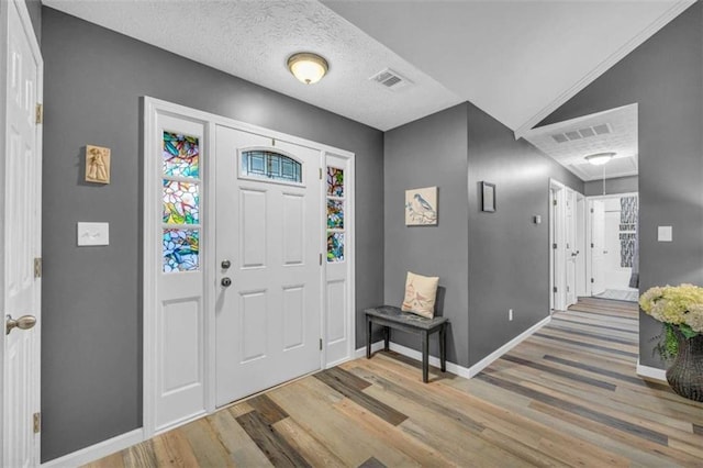 entryway with lofted ceiling, wood-type flooring, and a textured ceiling